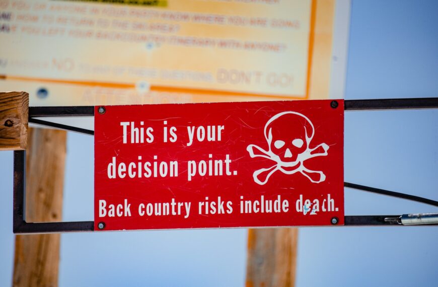 red and white signage on brown wooden post